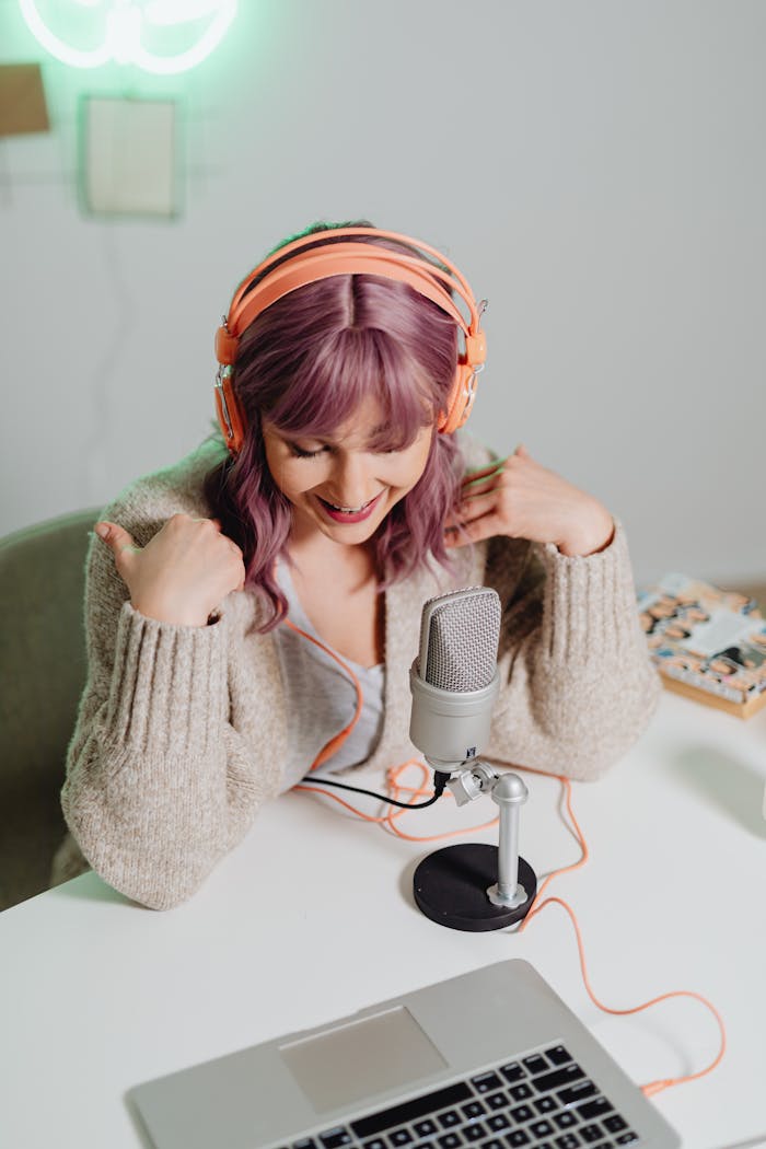 Young woman using microphone and headphones for podcast recording indoors.
